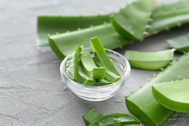 Taze kesilmiş aloe vera yaprakları gri tablo ile kase