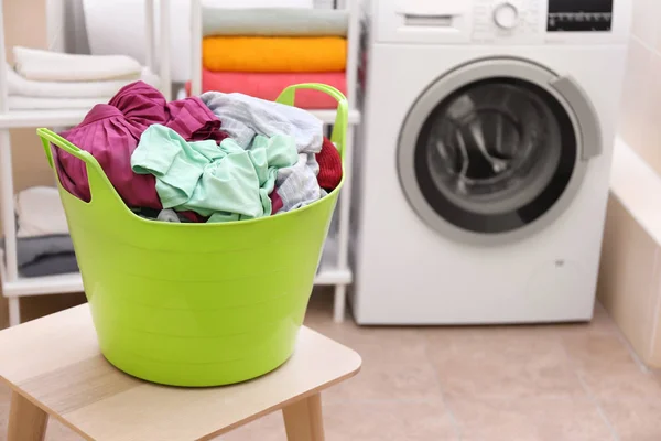 Laundry basket with dirty clothes on stool in bathroom