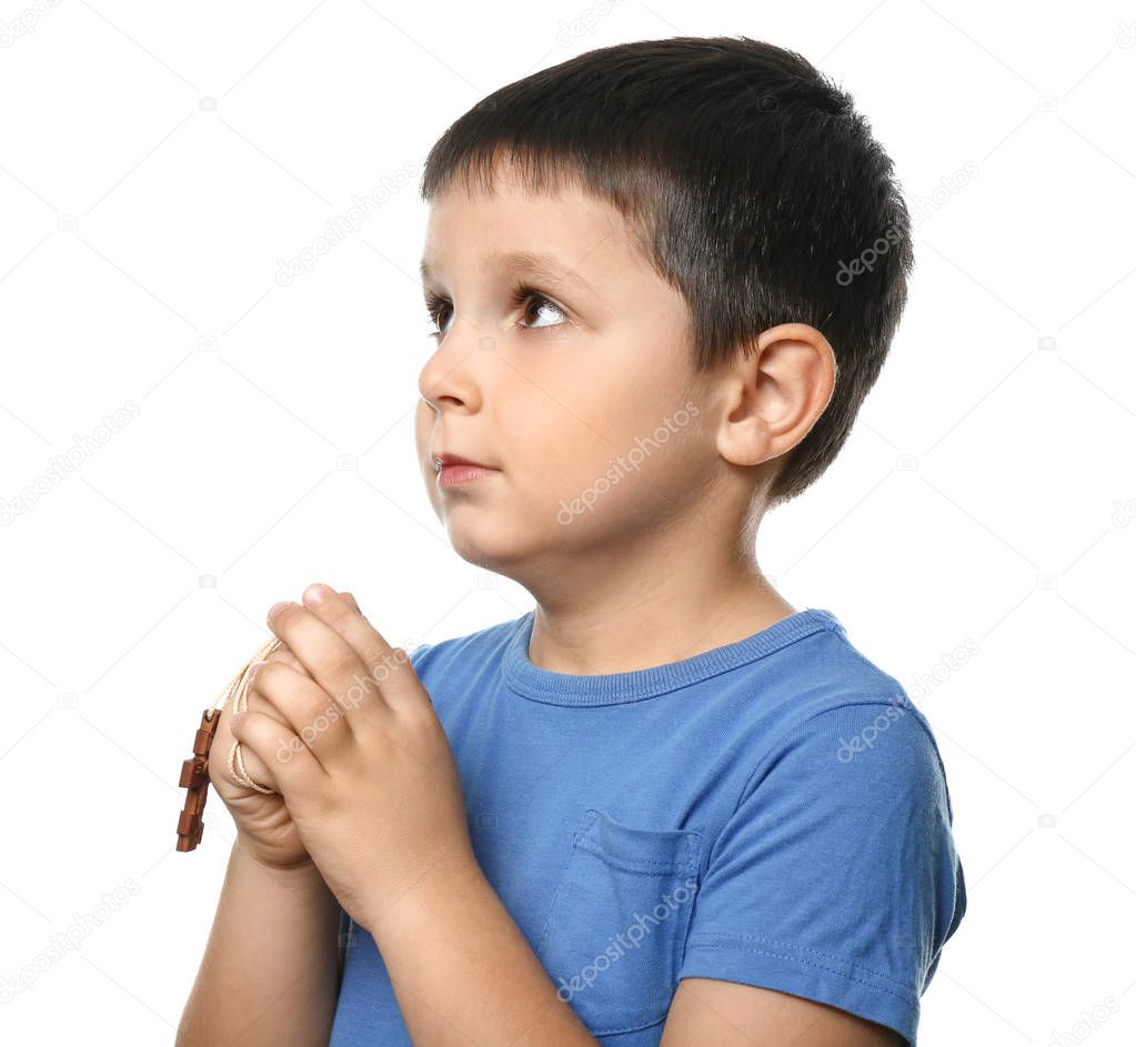 Little boy with cross praying on white background