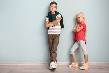 Sevimli çocuk ve kız renk duvarının yakınında Modern giyimleri