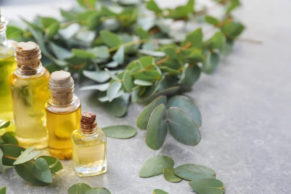 Bottles with essential oil and eucalyptus branches on table — Stock Photo, Image