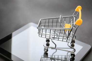 Küçük sepeti ve tablet bilgisayar masasında. Internet alışveriş kavramı