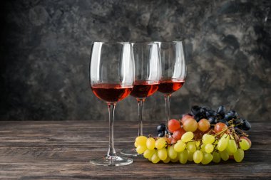 Gözlük şarap ve üzüm gri arka plan karşı ahşap tablo