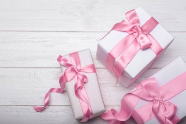 Beyaz ahşap zemin üzerinde pembe kurdeleler ile hediye kutuları
