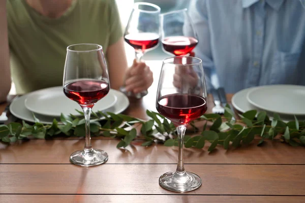 Glasses with red wine on table of friends celebrating holiday in restaurant