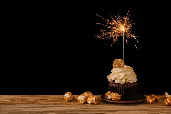 在黑暗的背景下 木桌上有火花和爆米花的美味巧克力纸杯蛋糕 — 图库照片