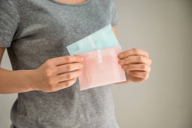 Adet yastıkları gri arka plan üzerinde tutan kadın
