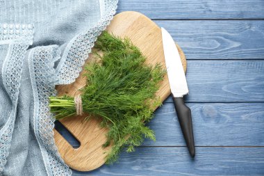 Ahşap tahta üzerinde bıçak ile taze aromatik dereotu demet