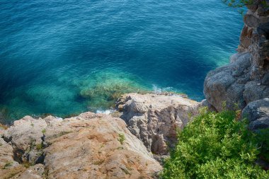 Güneşli mavi deniz kenarında kayalık sahil