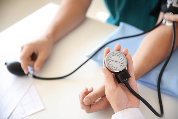 Женщина-врач измеряет артериальное давление пациента-мужчины в больнице
