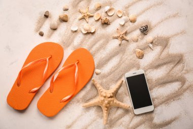 Farklı deniz kabukları, cep telefonu ve ışık arka plan üzerinde parmak arası terlik ile kompozisyon