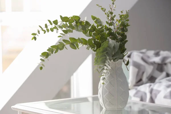グリーン ユーカリの枝ガラス テーブルの上の花瓶 — ストック写真