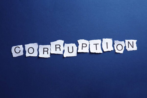 Torn pieces of paper with word CORRUPTION on blue background