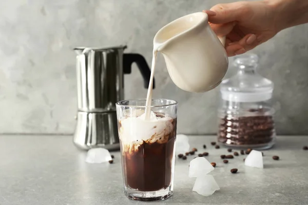 Wanita Menuangkan Susu Gelas Dengan Kopi Dingin Atas Meja Abu — Stok Foto