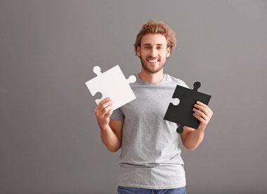 Gri zemin üzerine parçalı bulmaca parçaları ile genç adam