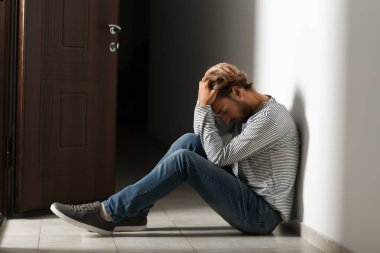 Karanlık koridorda katta oturan depresif genç adam