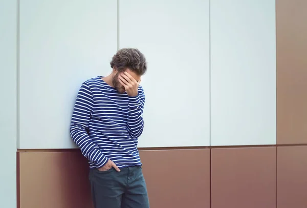 Stressed young man near wall outdoors