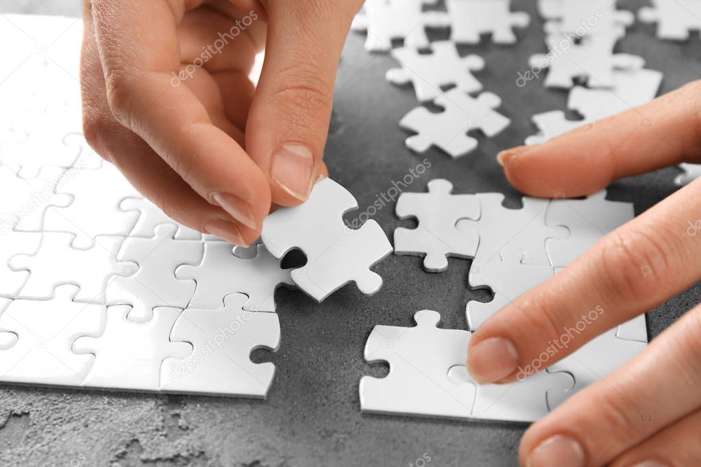 Woman doing jigsaw puzzle on table, closeup