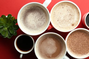 Düz renkli arka plan üzerinde lezzetli aromatik kahve ile fazla bardak yatıyordu