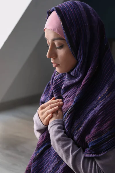 Young Muslim woman praying at home