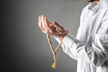 Genç Müslüman adam koyu arka plan üzerinde dua tespih ile