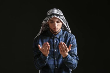 Genç Müslüman adam koyu arka plan üzerinde dua