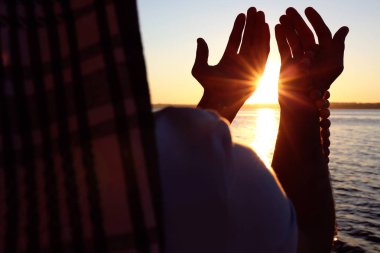 Gün batımında nehir kenarında dua genç Müslüman adam