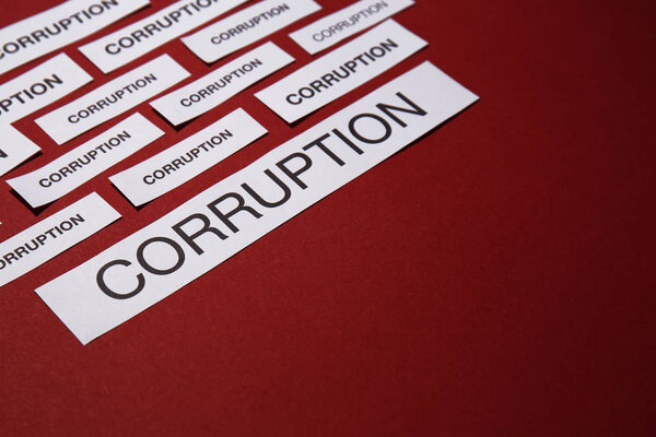 Pieces of paper with words CORRUPTION on red background