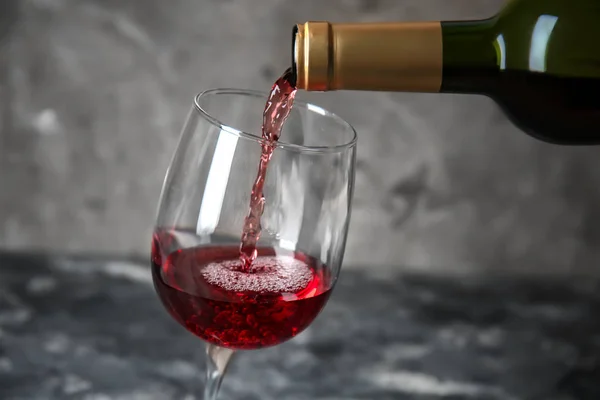 Ρίχνει Κόκκινο Κρασί Από Μπουκάλι Στο Ποτήρι Γκρίζο Φόντο — Φωτογραφία Αρχείου