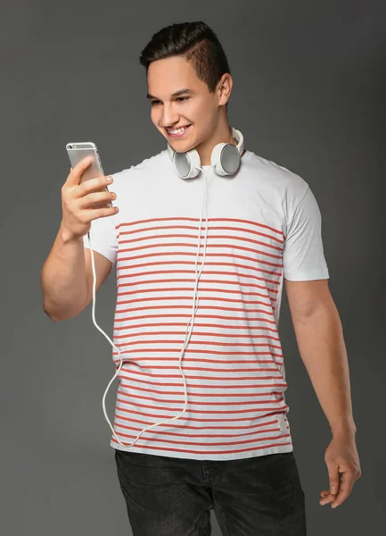 Młody Człowiek Słuchawek Telefonu Komórkowego Szarym Tle — Zdjęcie stockowe