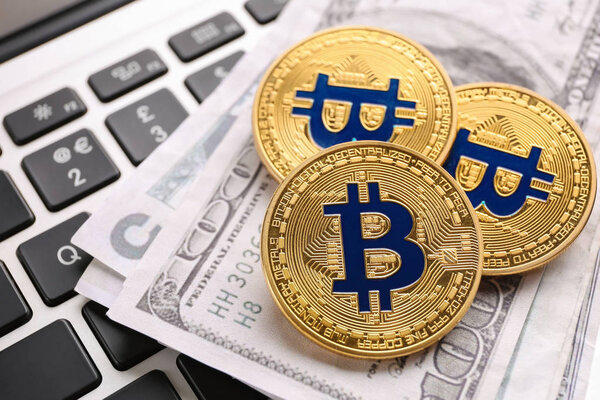 Золотые биткоины и долларовые банкноты на клавиатуре ПК
