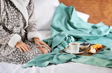 Genç kadın yatakta lezzetli kahvaltı