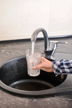 Kadın cam su musluk ile doldurma