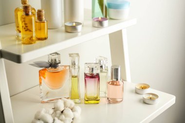 Güzel şişe parfüm, pamuk ve beyaz masa üzerinde yanan mumlar