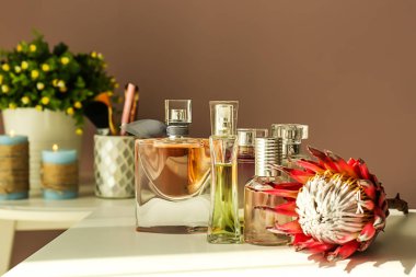 Şişe parfüm ve beyaz masada çiçek
