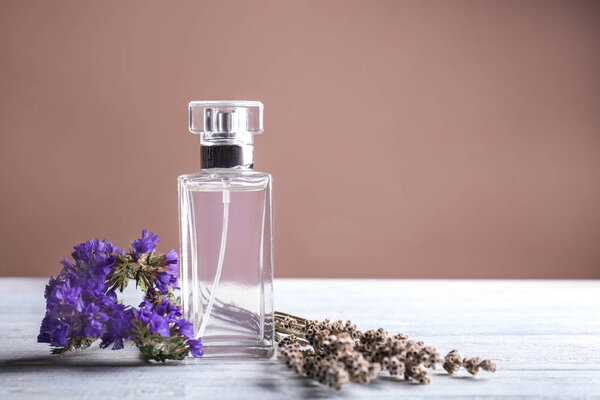 Прозрачная бутылка духов с цветами на белом столе
