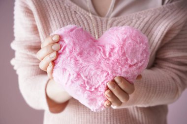 Kuştüyü yastık kalp şeklindeki renk arka planda, closeup tutan kadın