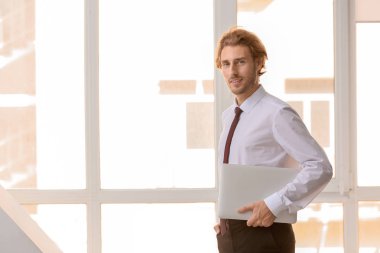 Pencere yakınındaki dizüstü bilgisayar ile kendine güvenen iş adamı