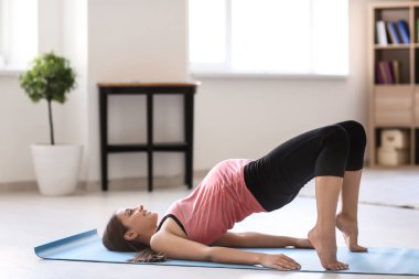 Genç hamile kadın evde yoga yapıyor.