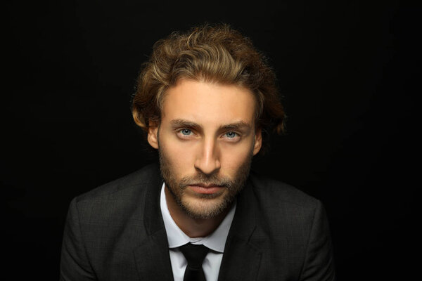 Portrait of handsome businessman against black background