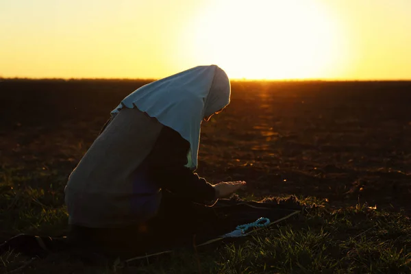 Young Muslim woman praying outdoors at sunrise