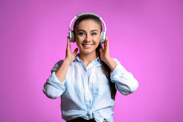 Красивая женщина слушает музыку на цветном фоне
