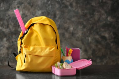 Okul malzemeleri ile gri arka plan üzerinde sırt çantası
