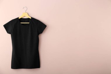 Askı ile renk arka plan üzerine boş siyah t-shirt