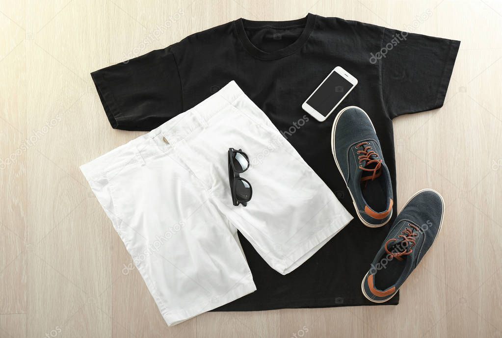 Stylish outfit with shoes and mobile phone on wooden background