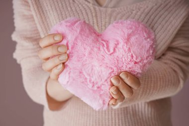 Kuştüyü yastık kalp şeklindeki renk arka planda, closeup tutan kadın