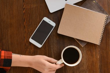 Cep telefonu ve dizüstü ile masada kahve içme kadın