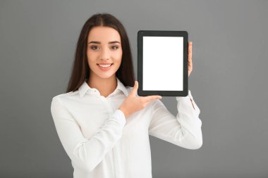 Tablet bilgisayar gri arka plan üzerinde tutan genç kadın