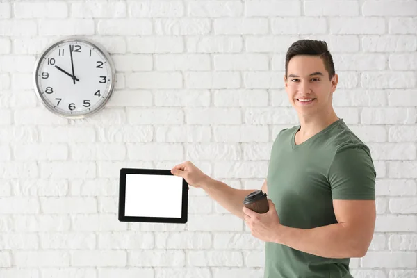 Young Man Holding Tablet Computer White Brick Wall Clock — Stock Photo, Image