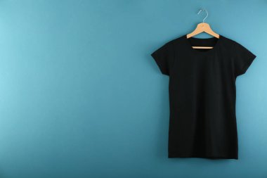 Askı ile renk arka plan üzerine boş siyah t-shirt
